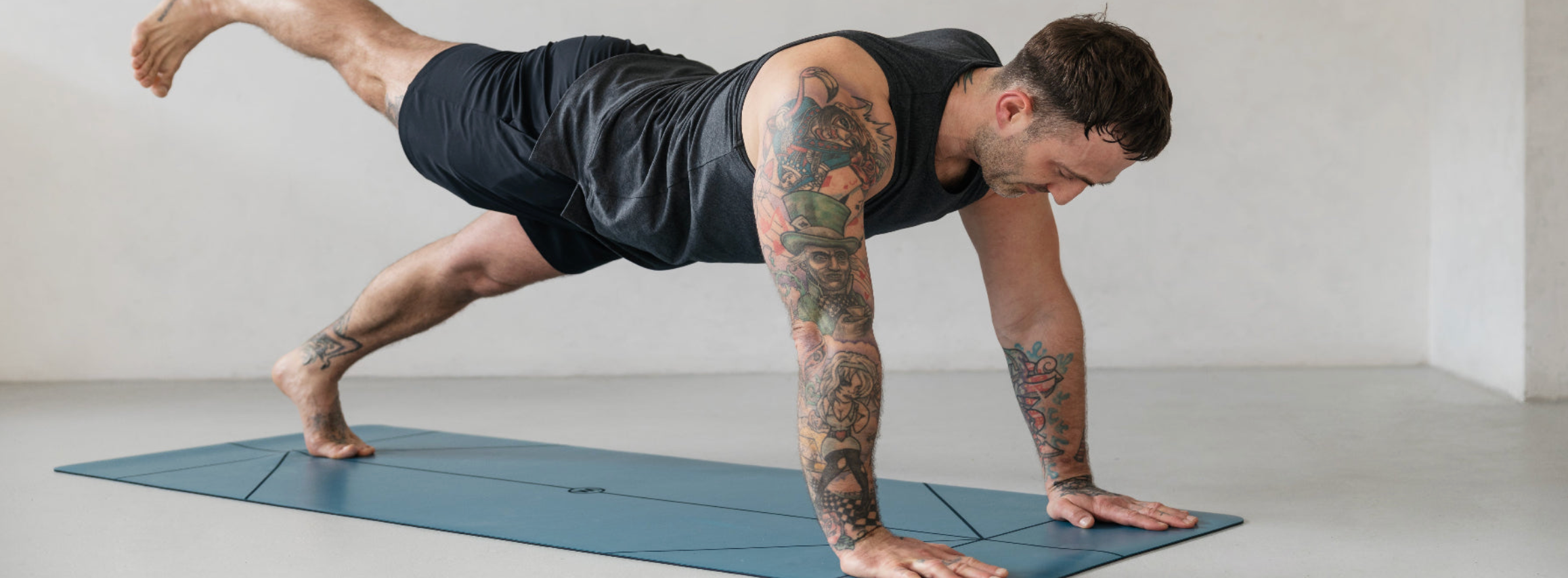 man wearing hot yoga shorts doing yoga on a mat