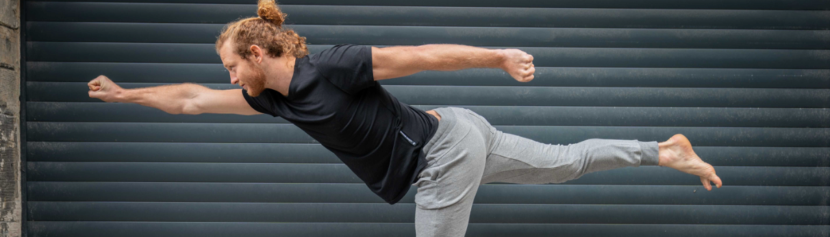 man wearing grey mens yoga pants doing a yoga pose