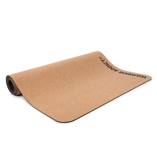 Unrolled cork yoga mat with "WARRIOR ADDICT" printed on it.