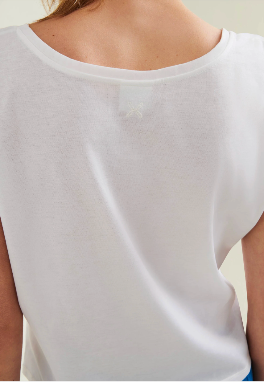 White sleeveless top worn by a person on a plain background