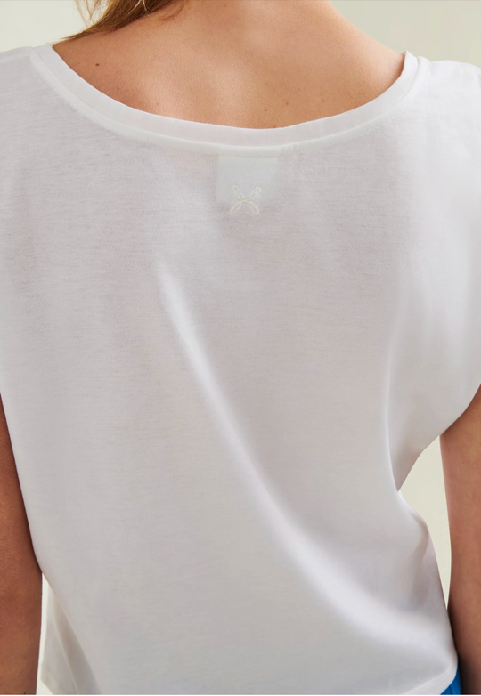 White sleeveless top worn by a person on a plain background