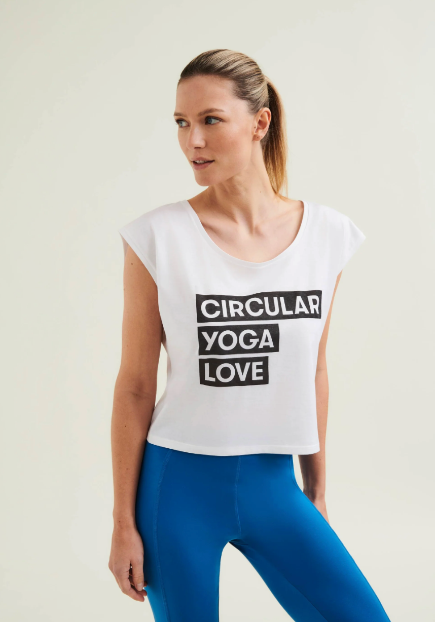 Woman wearing a white t-shirt with 'Circular Yoga Love' text and blue leggings on a light background