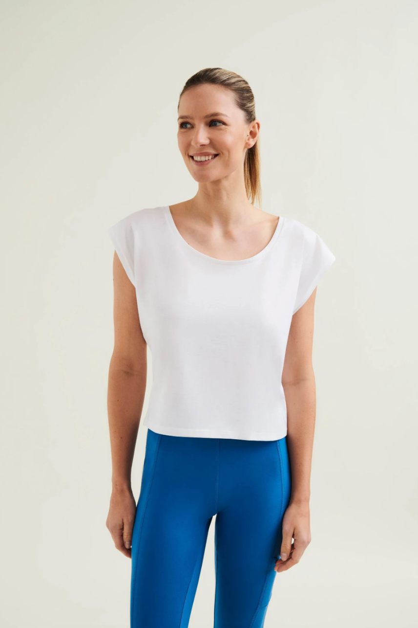 Woman wearing a white top and blue leggings on a plain background