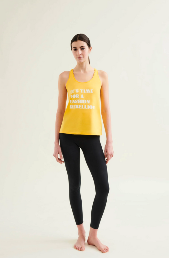 Woman wearing a yellow tank top with text and black leggings on a white background