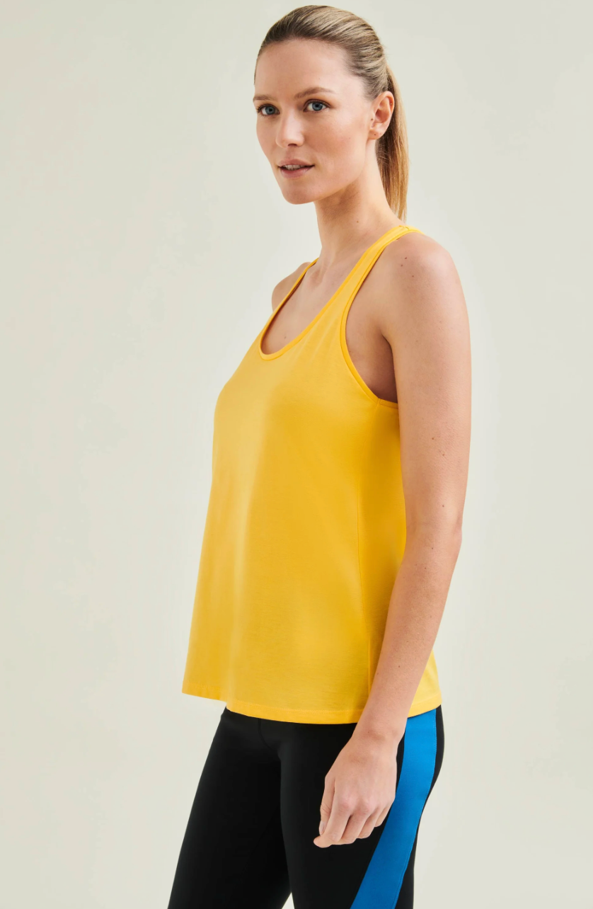 Woman wearing a yellow tank top and black leggings with blue accents on a light background