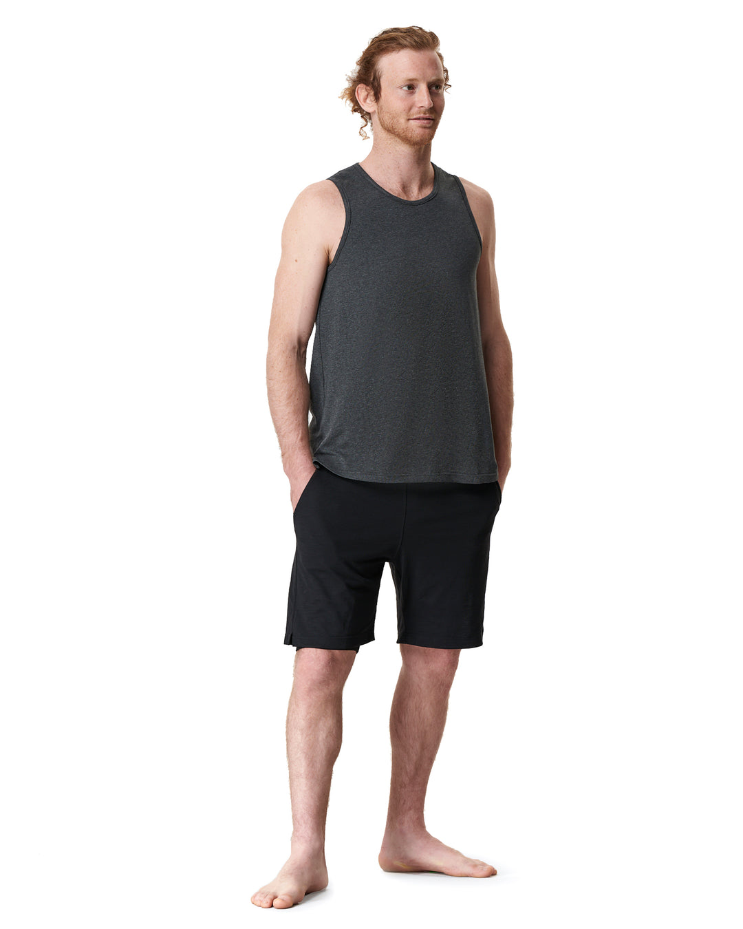 Man standing in a gray tank top and black shorts.