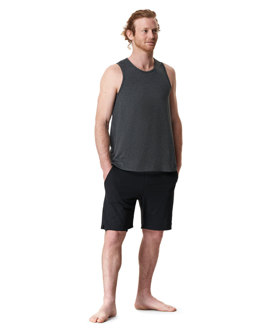 Man standing in a gray tank top and black shorts.