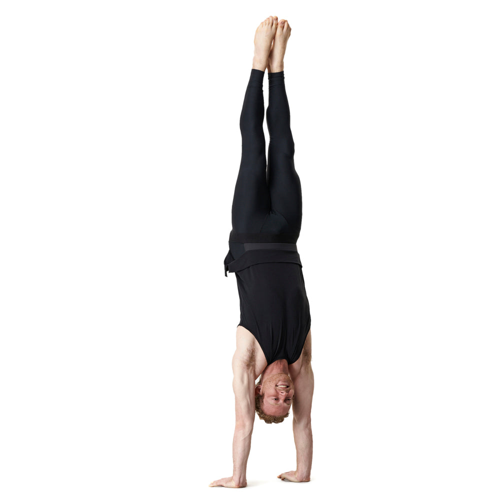 A man in black athletic clothes doing a handstand.