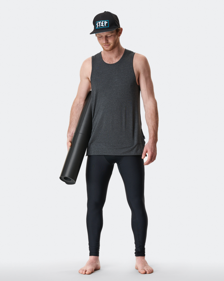 man wearing mens yoga top and mens yoga leggigs carrying a yoga mat 