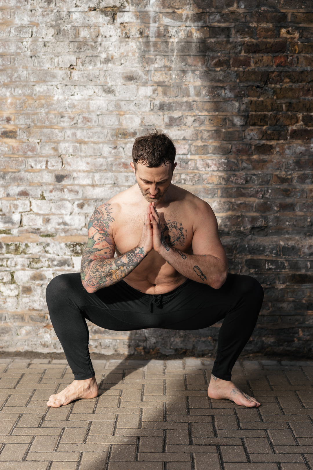 Man in yoga pose against brick wall.