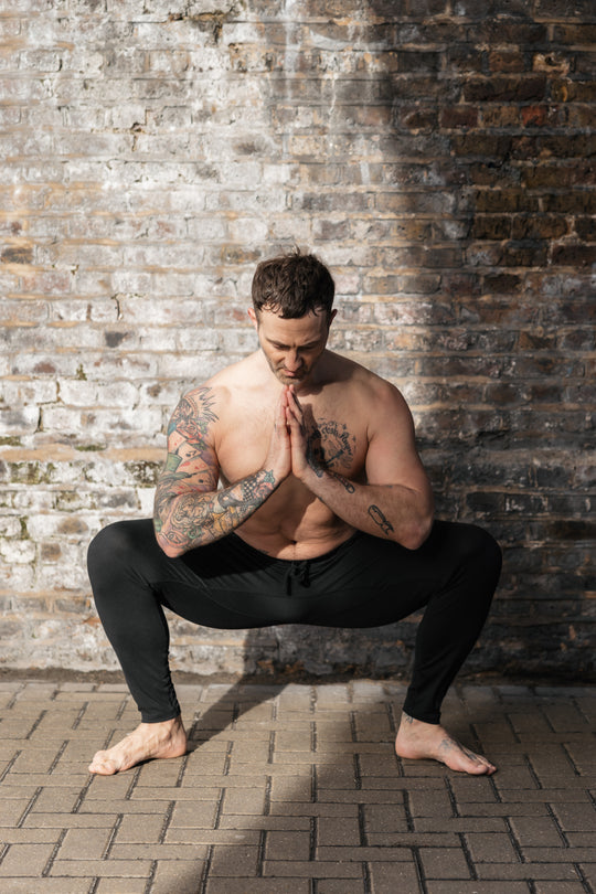 Man in yoga pose against brick wall.