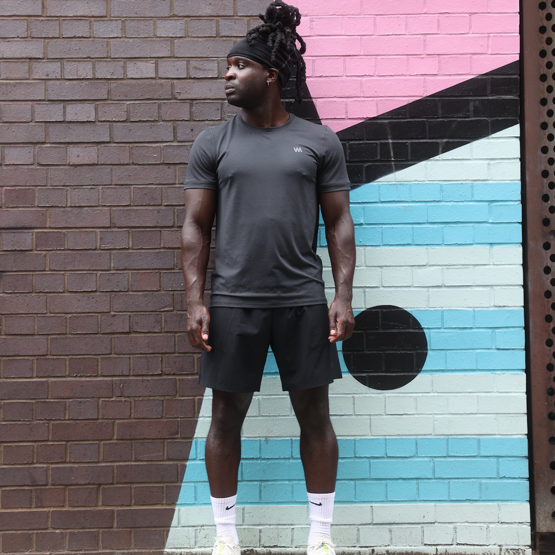 Man in Warrior Addict activewear standing in front of a colorful brick wall.