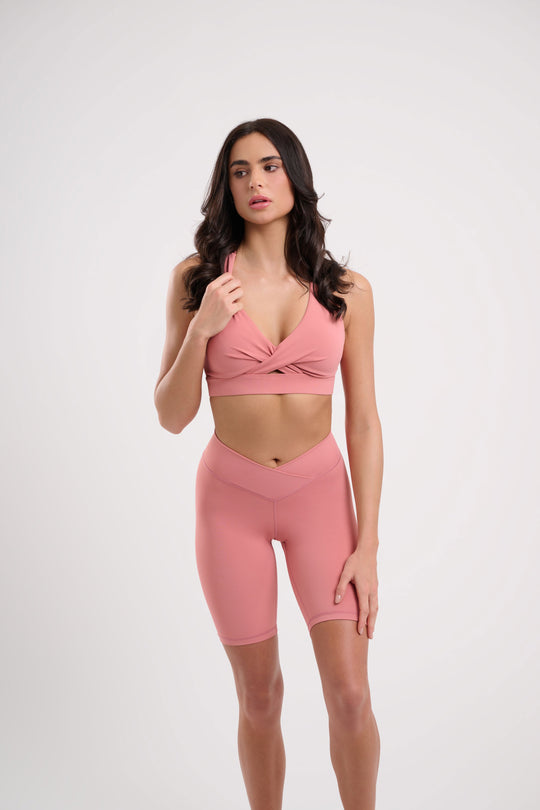 A woman wearing a pink sports bra and matching athletic shorts.