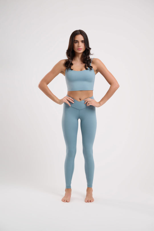 Woman in light blue athletic wear standing with hands on hips.