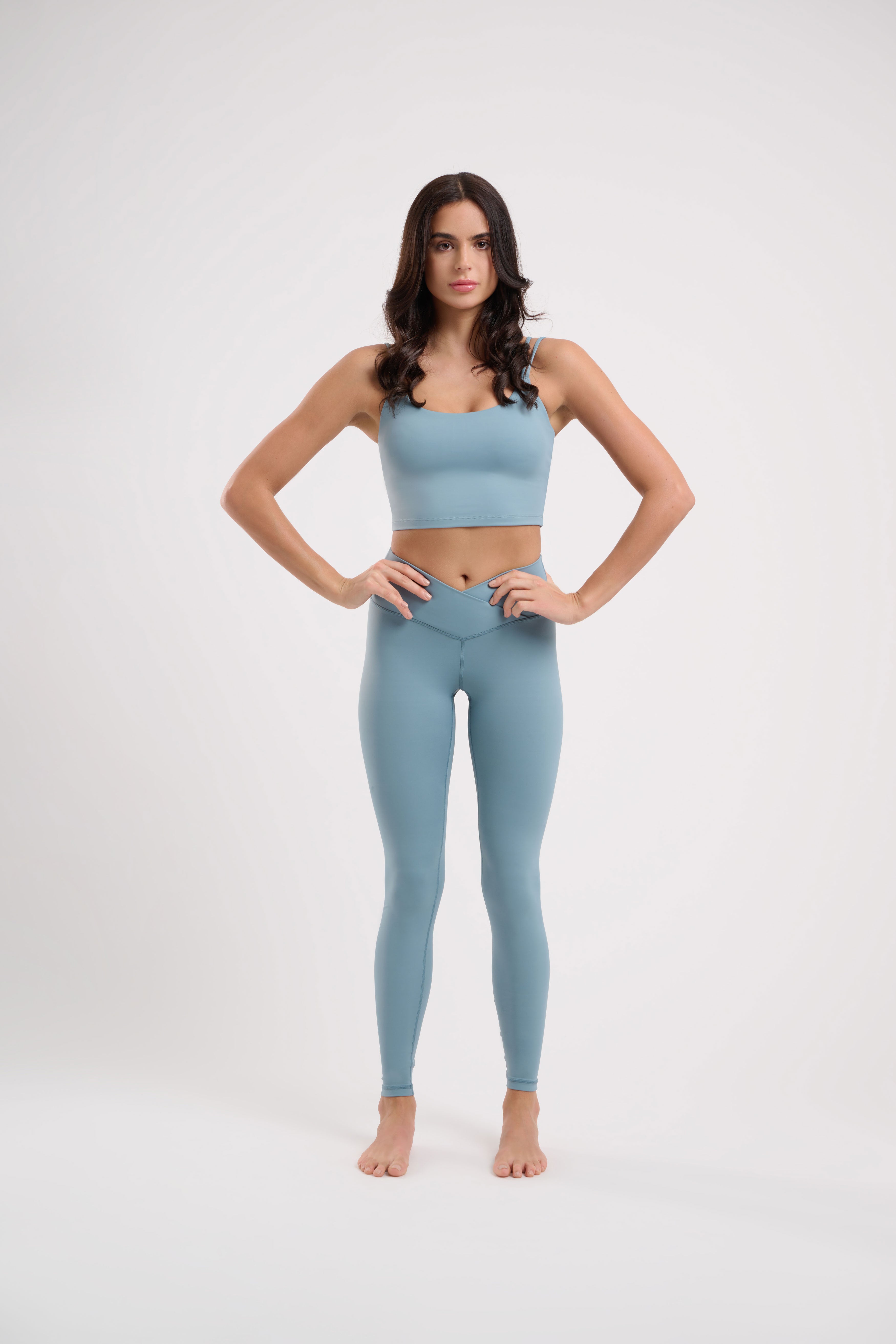 Woman in light blue athletic wear standing with hands on hips.