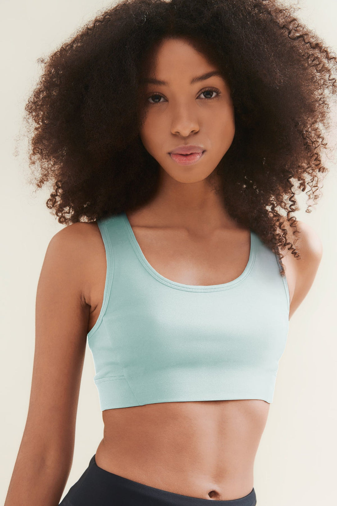 Woman with curly hair in a turquoise crop top.