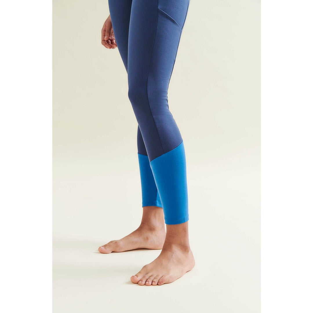 Person wearing two-tone blue leggings standing barefoot.