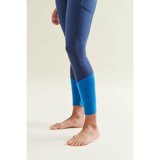 Person wearing two-tone blue leggings standing barefoot.