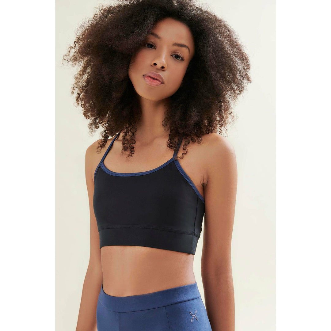 Woman in a black sports bra and blue leggings.