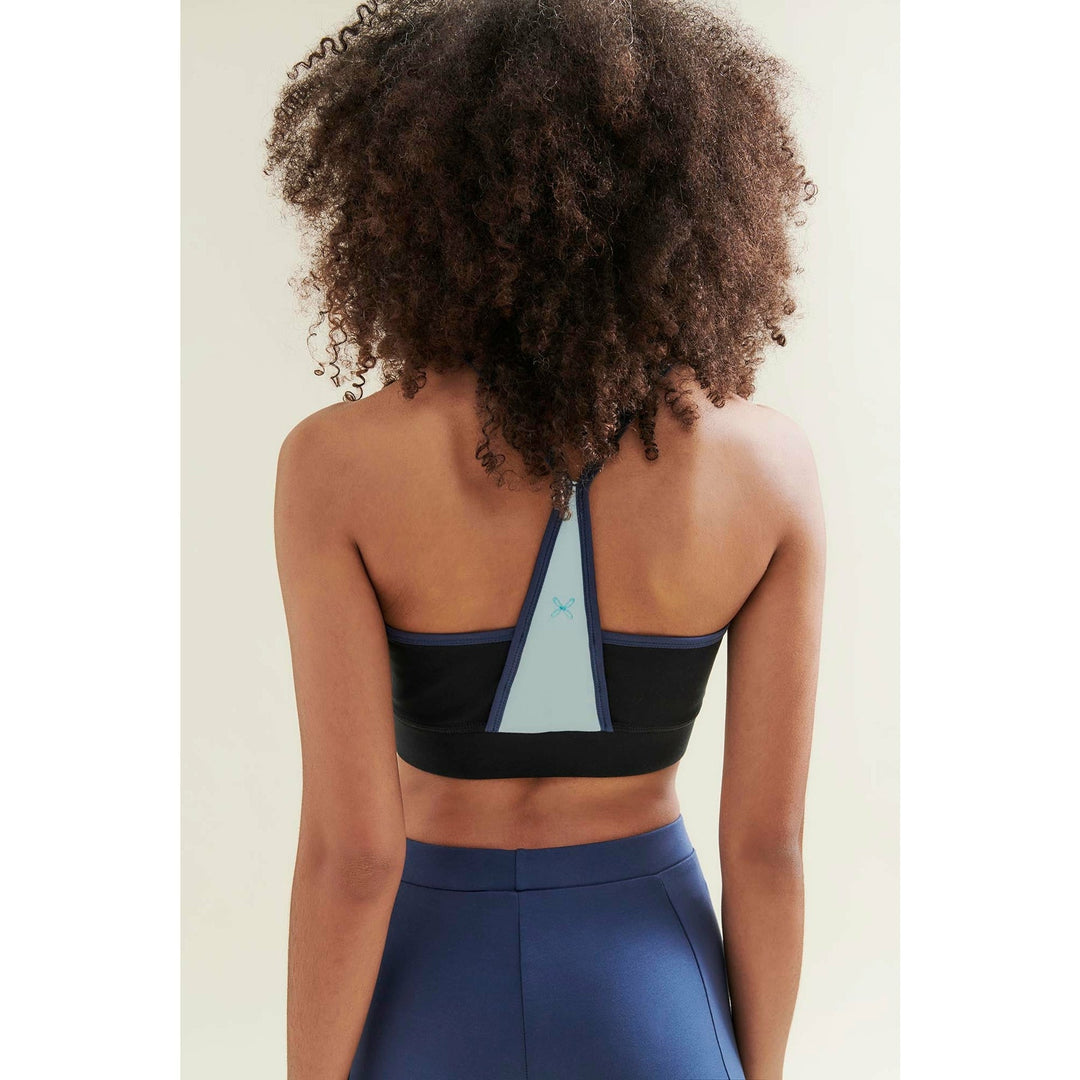 Rear view of a woman wearing a black and blue sports bra and leggings.