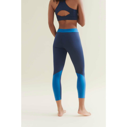 Woman from behind wearing a two-toned blue sports bra and leggings.