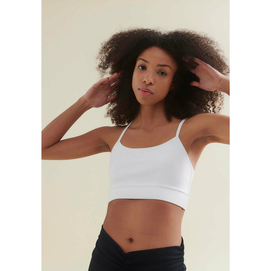 Woman in white sports bra and black shorts.
