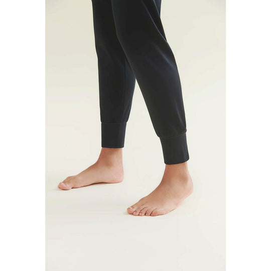 A person wearing black joggers and standing barefoot.