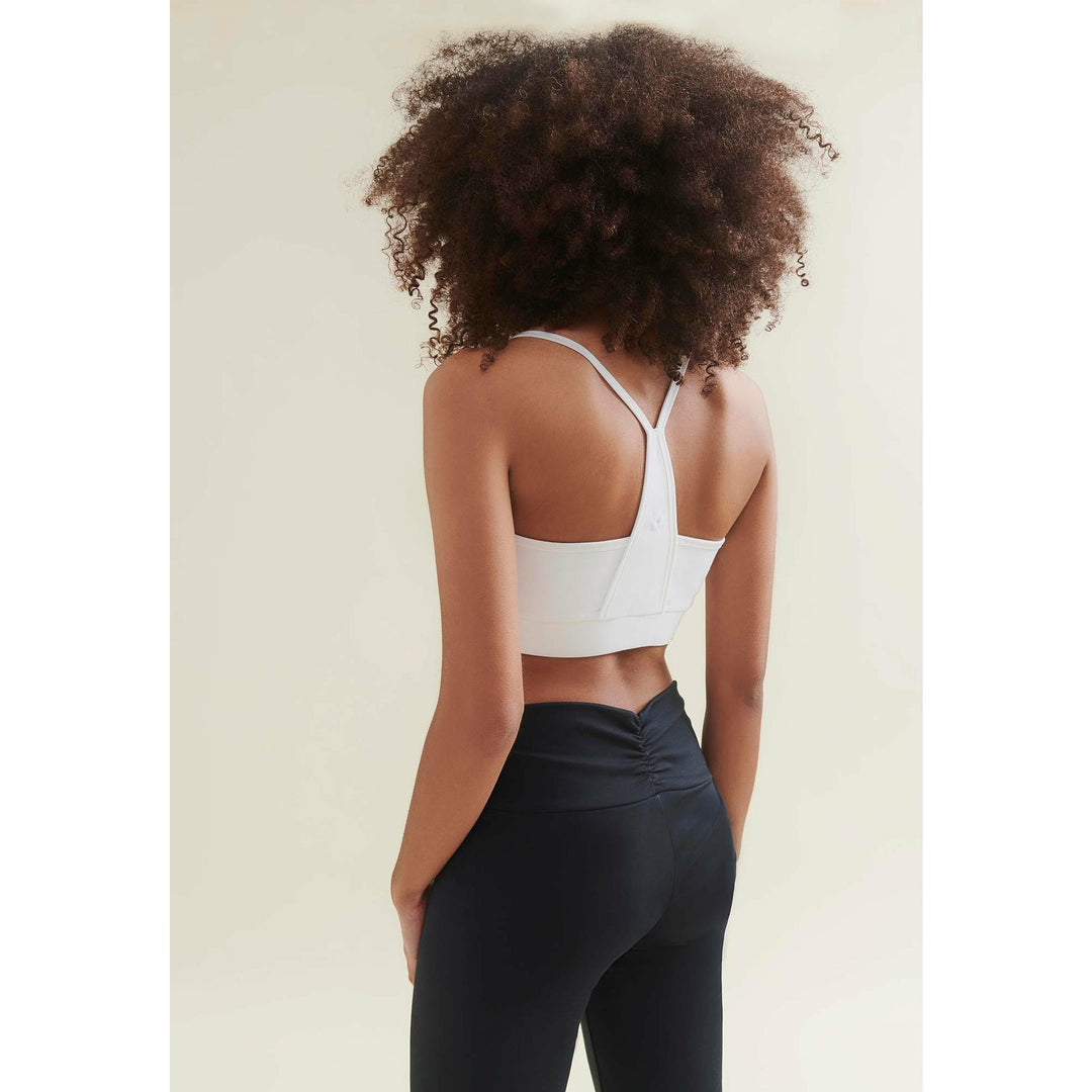 Woman wearing a white sports bra and black leggings from behind.
