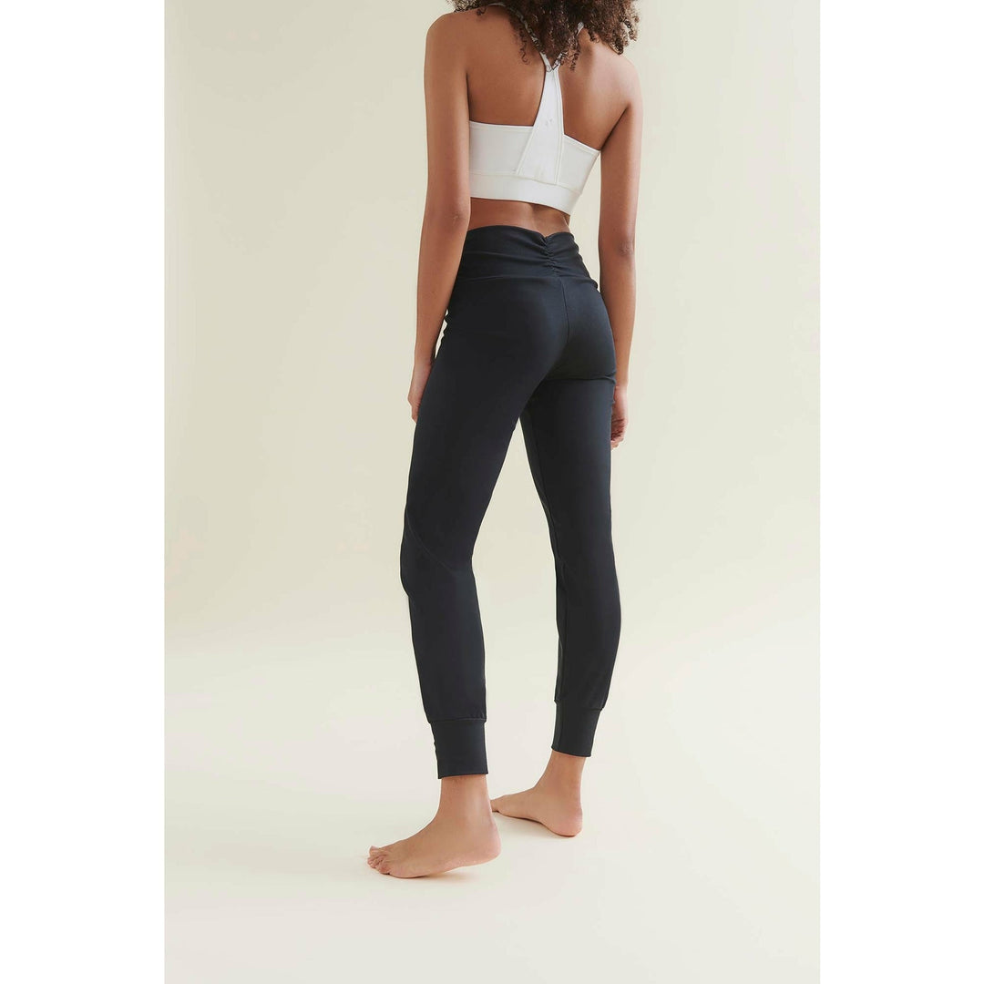Woman wearing a white sports bra and black leggings.
