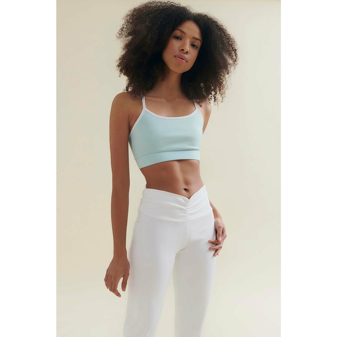 Woman in light blue crop top and white leggings.