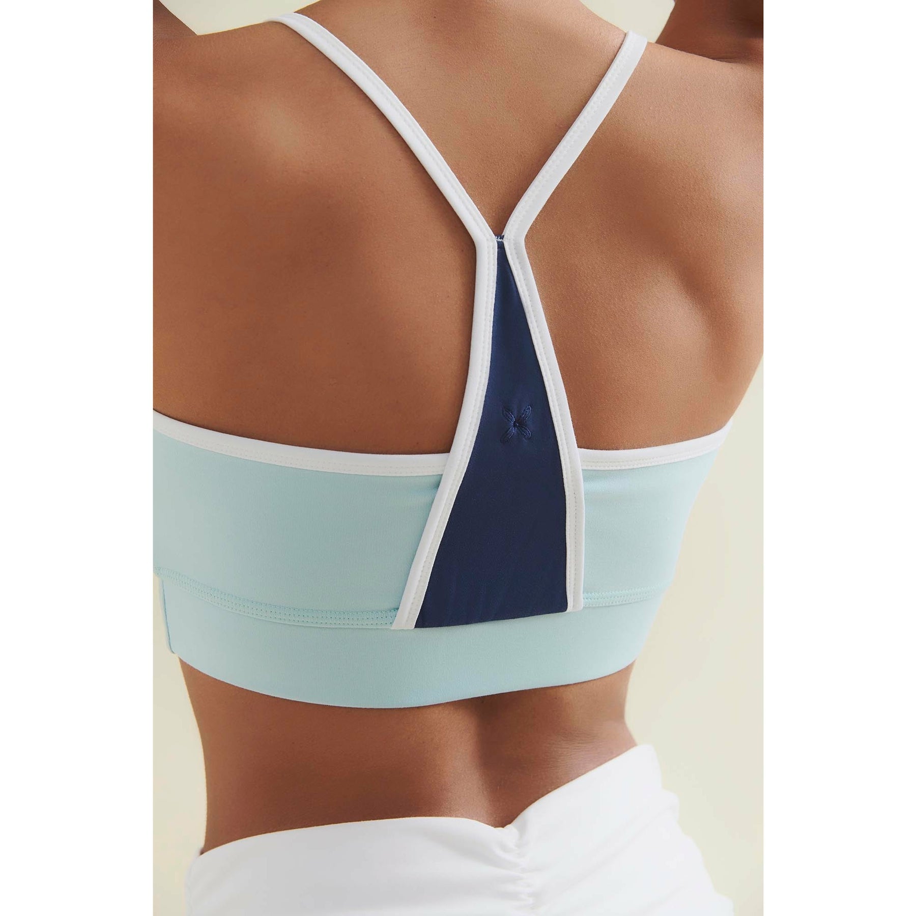Close-up of the back of a light blue and navy sports bra with white straps.