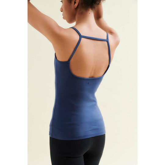 Woman in blue tank top with back detail and black leggings.