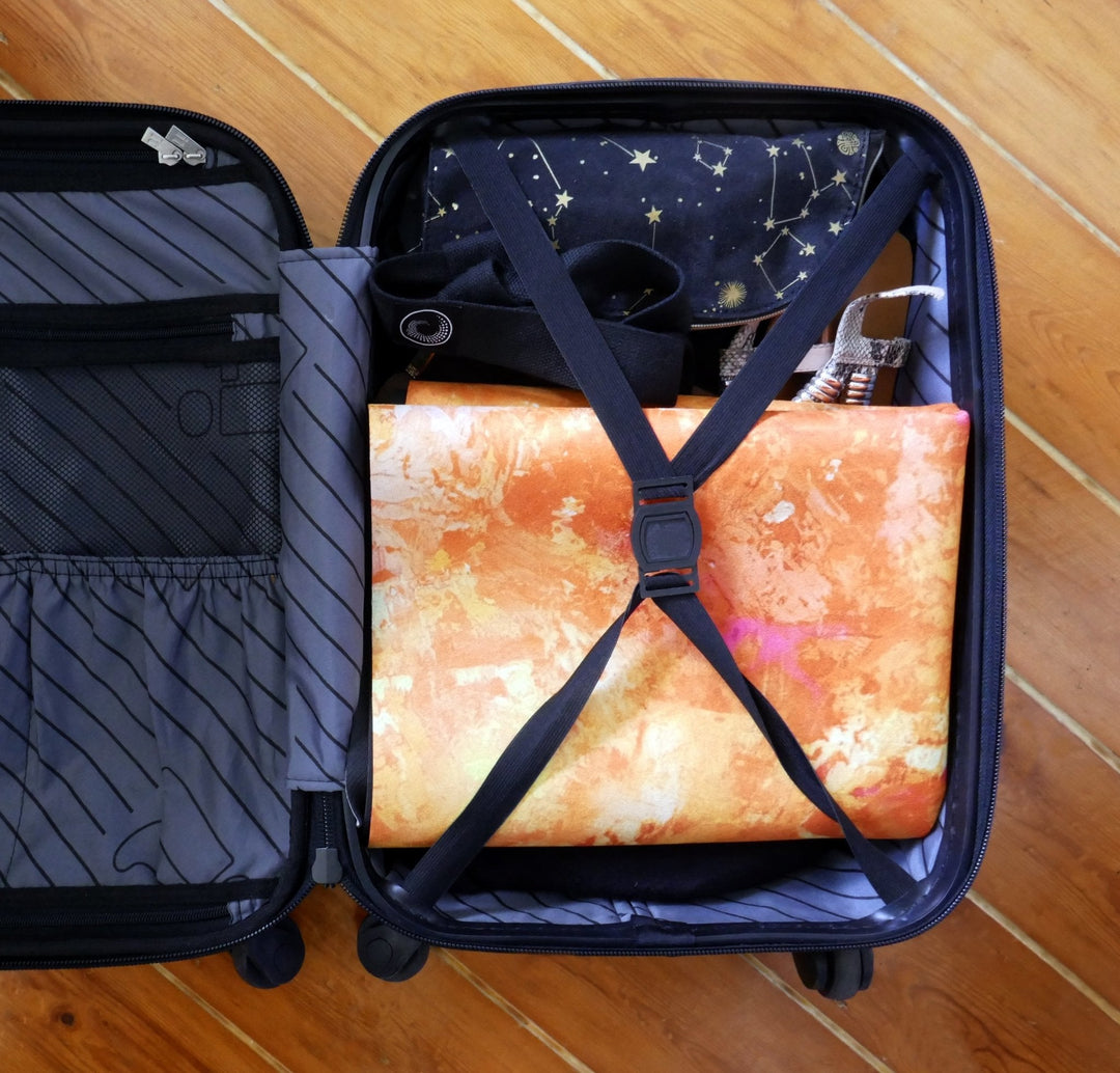 Open suitcase packed with clothing and shoes on a wooden floor.