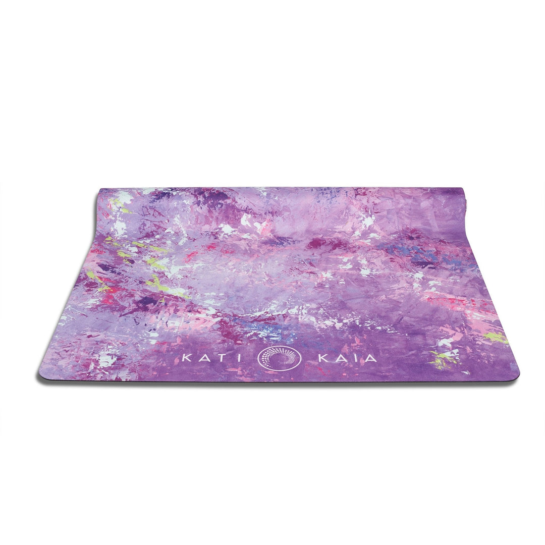 A purple abstract yoga mat with the brand "Kati Kaia" on the bottom.