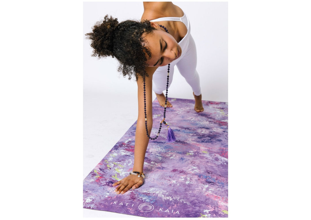 Woman in white doing yoga on a purple painted yoga mat.