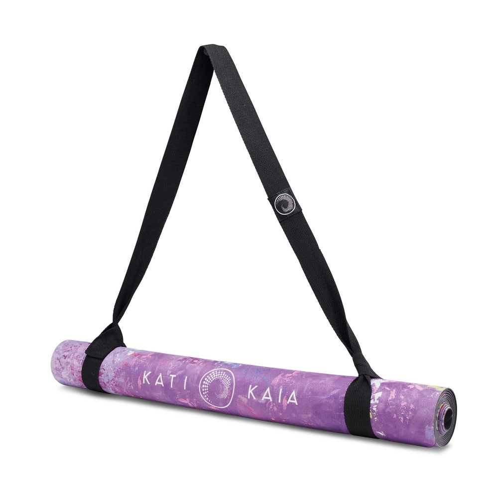 Rolled purple yoga mat with black carrying strap.