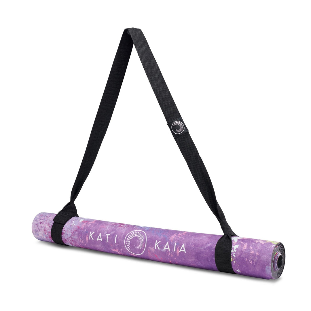 Rolled purple yoga mat with black carrying strap.