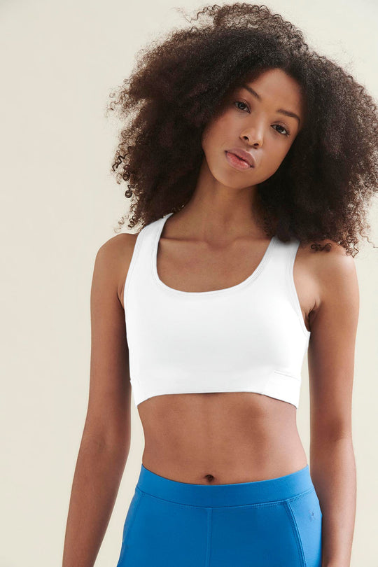 Woman wearing a white sports bra and blue leggings.