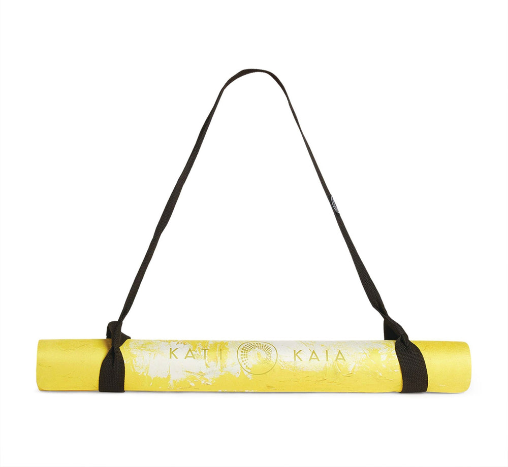 Rolled yellow yoga mat with brown straps.