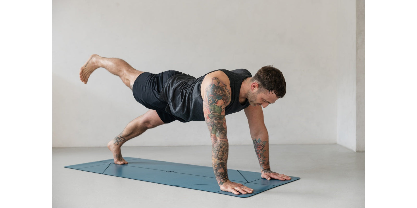man in mens yoga shorts and top on blue yoga mat 