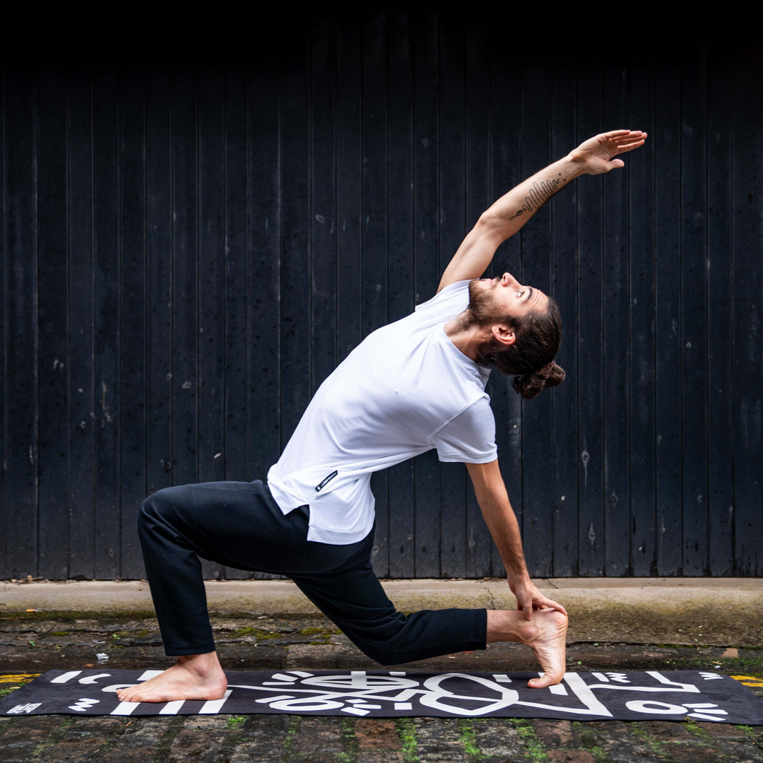 Person practicing yoga on a mat with a black wall background