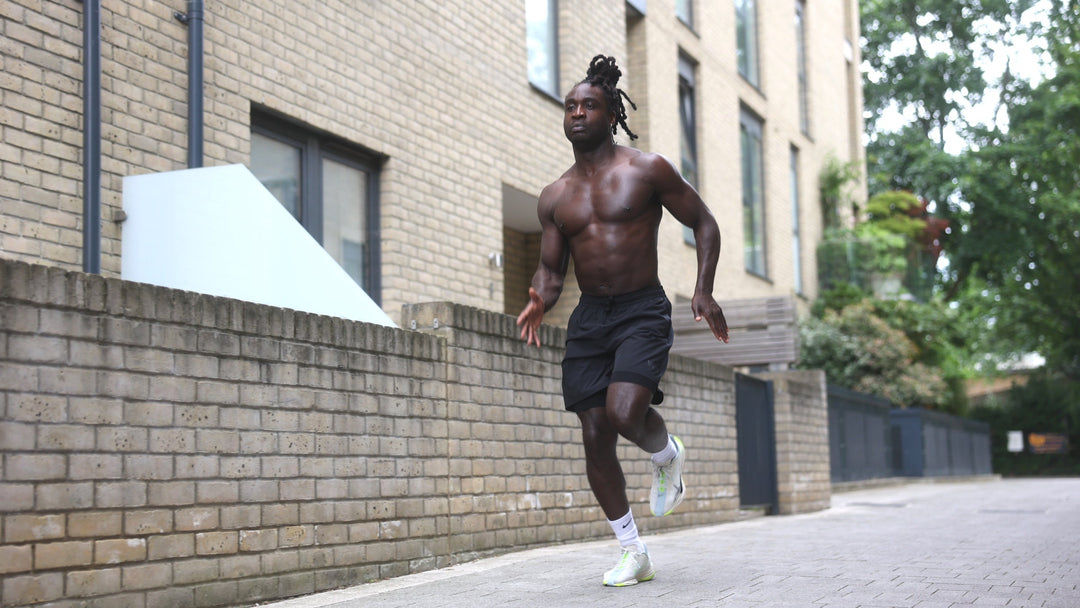 Man running on a street with a brick building in the background