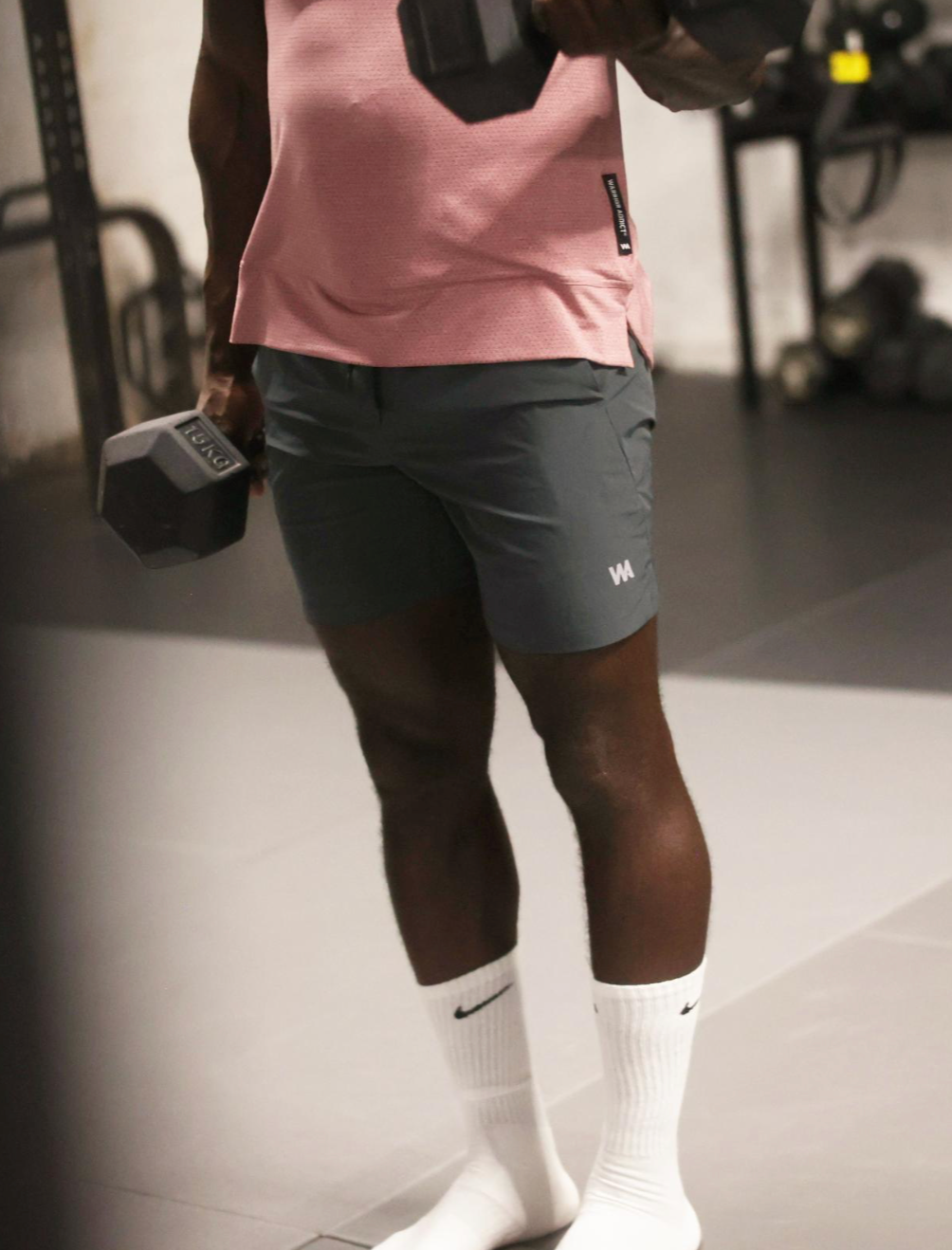 Person exercising with dumbbells in a gym setting wearing warrior addicts mens activewear shorts 