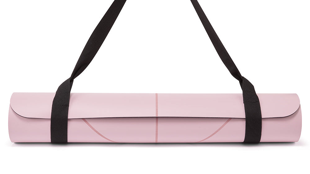 A rolled pink yoga mat with black carrying straps, shown against a plain white background.