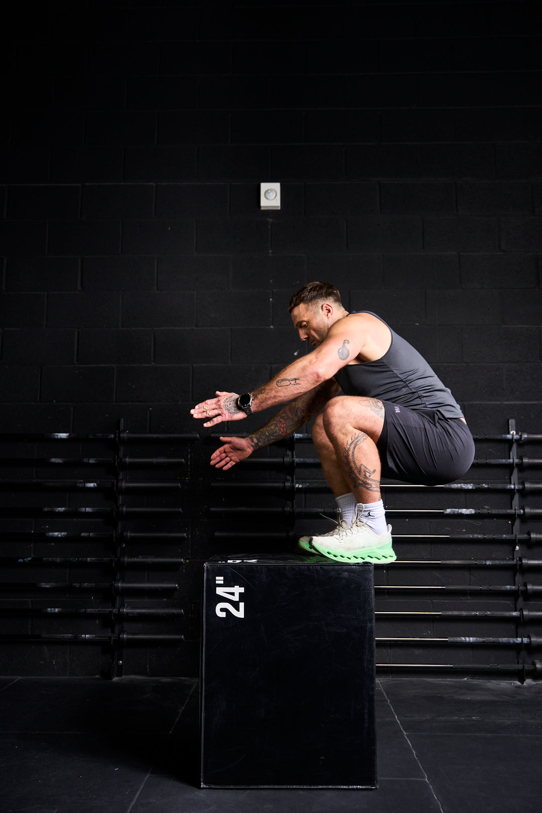 Man performing a jump onto a black box in a gym setting wearing warrior addict activewear