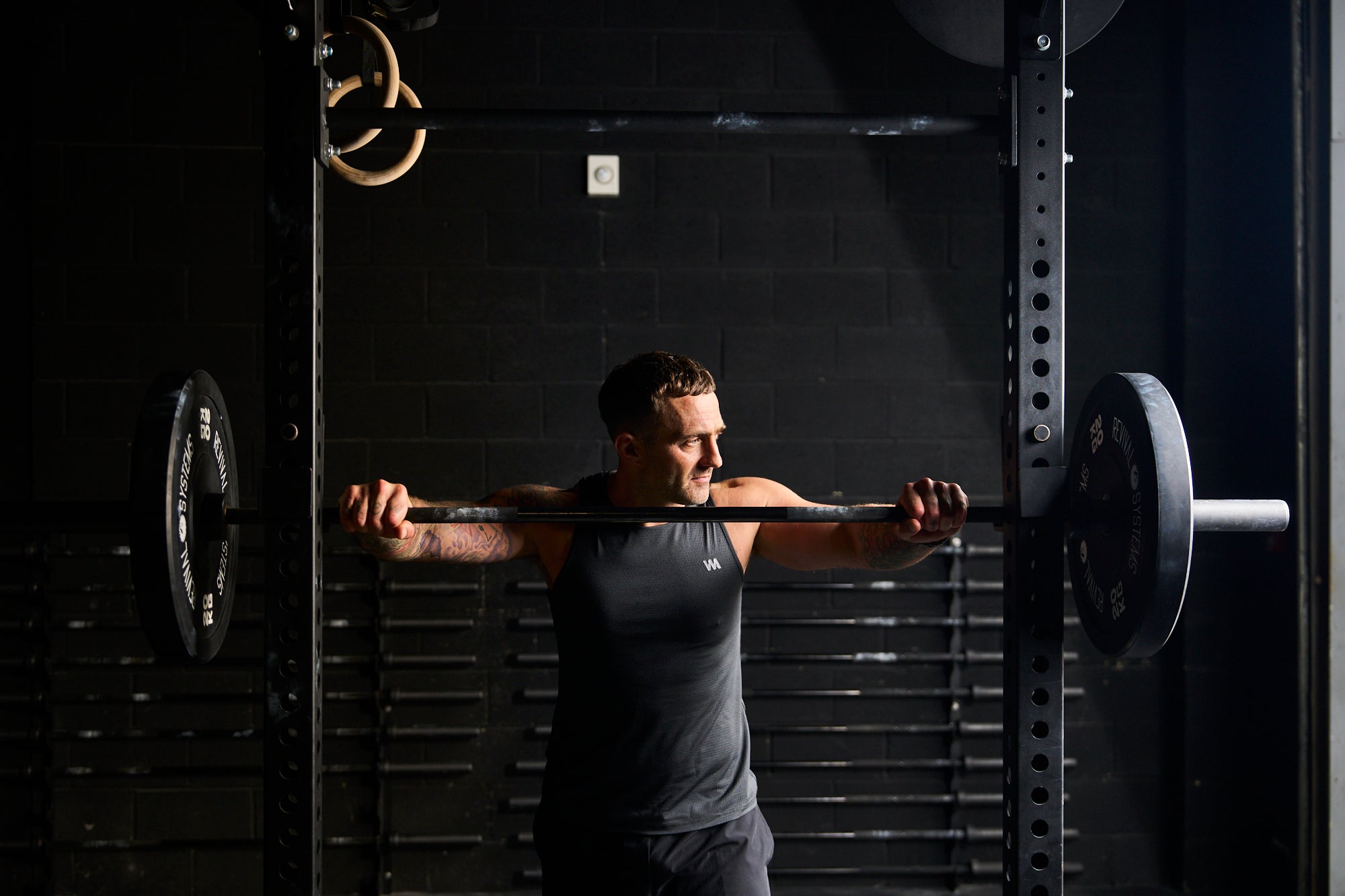 Man lifting a barbell in a gym setting wearing warrior addict activewear 