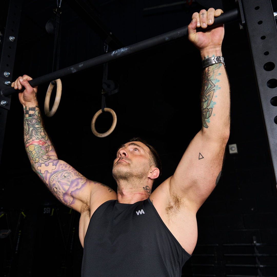 Man performing pull-ups on a bar in a gym setting