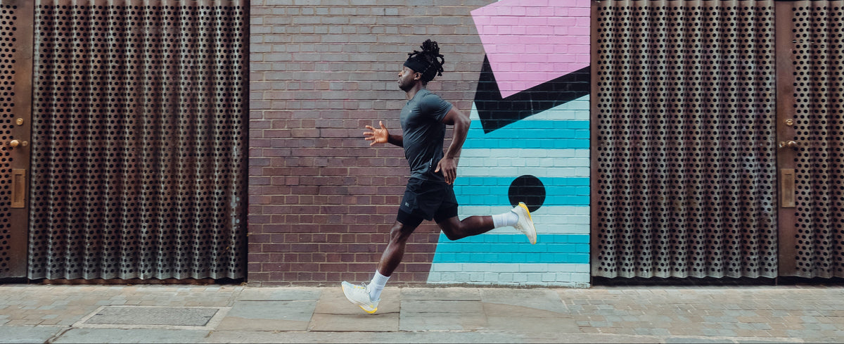 Person running in front of a colorful mural on a building
