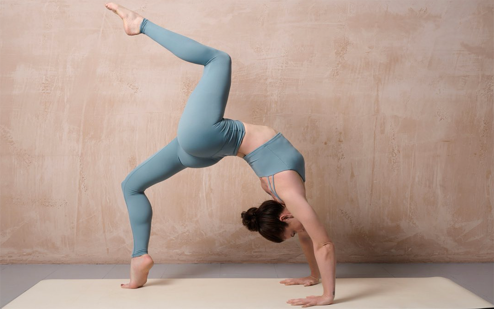 girl practicing yoga in bridge pose in blue yoga leggings
