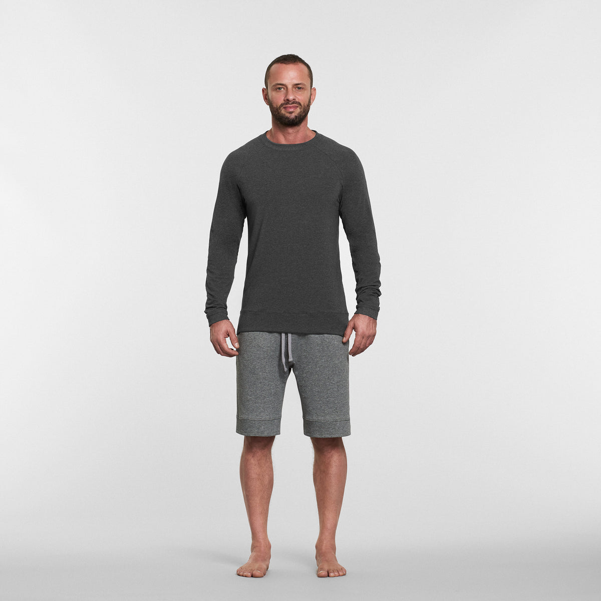 man wearing grey long sleeved yoga top and grey yoga shorts 